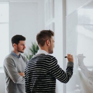 men writing on white board