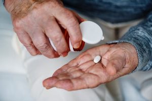 closeup man pouring white pill into hand from bottle