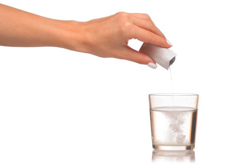 woman's hand pouring powder from packet into glass of water - powdered