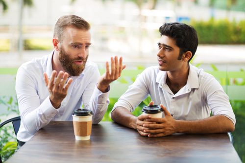 two men talking over coffee outdoors - sponsors