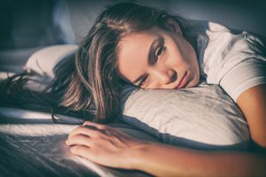 sleepy or high looking woman laying in bed - tramadol addiction